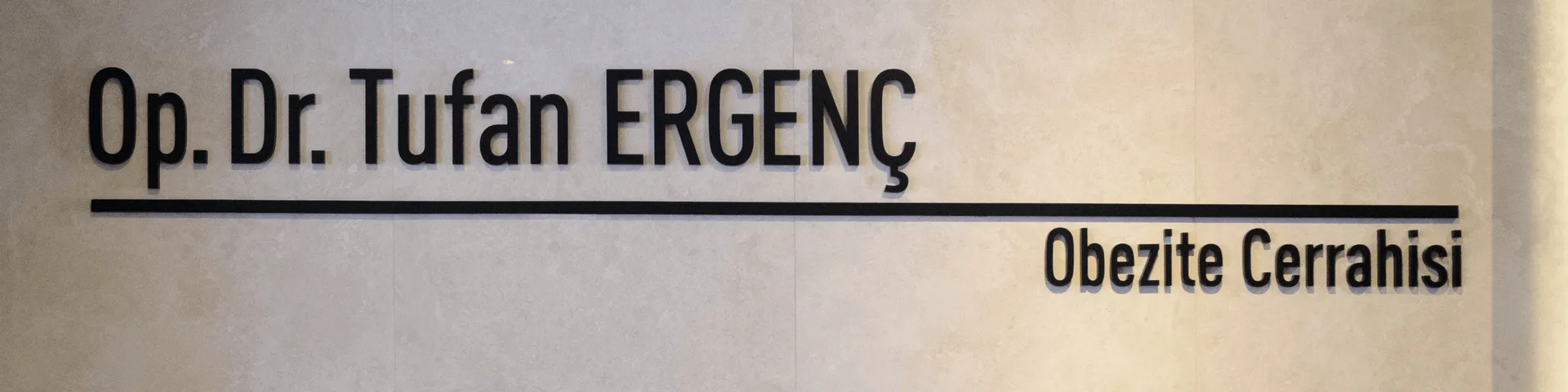 Kliniğin traverten duvarındaki tabela: Op. Dr. Tufan Ergenç — Obezite Cerrahisi.